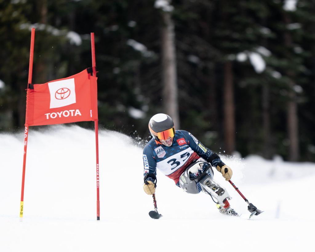 A mono skier rounds a gate at an adaptive alpine ski race.