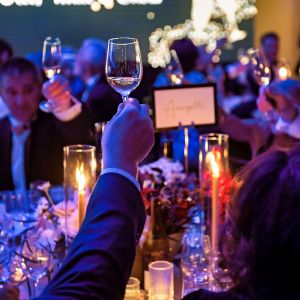 People holding up wine glasses in a toast at the Red, White & Snow Gala.